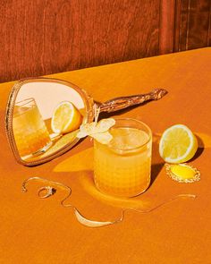 two glasses with lemons on a table next to an oval mirror and a rope