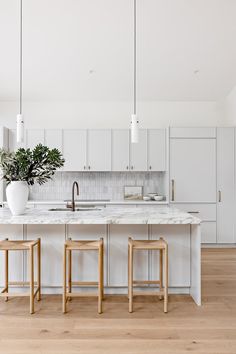 a kitchen with two stools next to an island in front of a sink and stove