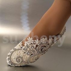 a woman's feet in white shoes with beaded lace and pearls on them