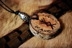 a wooden pendant with an arrow on it sitting on top of a piece of wood