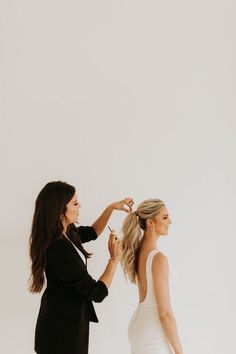 two women standing next to each other in front of a white wall