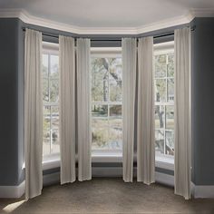 an empty room with three windows and two drapes on the window sill,