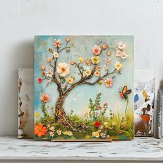 a painting with flowers and butterflies on it sitting on a shelf next to other items