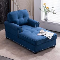 a blue chaise lounge chair sitting on top of a rug next to a window