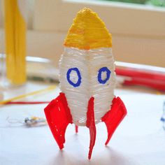 a plastic model of a rocket ship with blue eyes and yellow hat on it's head