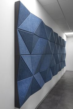 a blue wall hanging on the side of a white wall next to a gray floor