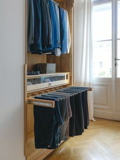 an open closet with clothes hanging on the wall and wooden flooring in front of it