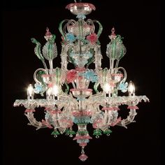 a chandelier with many lights and flowers on the bottom tier, against a black background