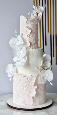 a three tiered cake with white flowers on top