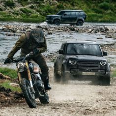 a man riding on the back of a motorcycle next to a black pickup truck driving down a muddy road