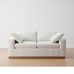 a white couch sitting on top of a hard wood floor next to a white wall