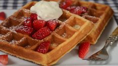 two waffles on a plate with strawberries and whipped cream