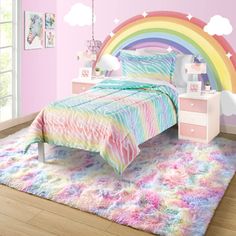 a child's bedroom with pink walls and rainbow bedding