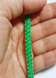 a person holding a green string in their left hand and the end of it being crocheted