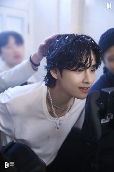 a young man is getting his hair brushed by another person with a camera in front of him