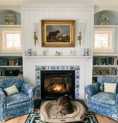 a living room with two blue chairs and a fire place in the middle of it