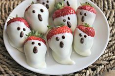 chocolate covered strawberries with white frosting in the shape of ghost faces on a plate