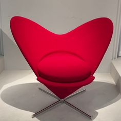 a red heart shaped chair sitting on top of a white floor