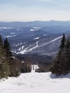 a snow covered ski slope with trees and mountains in the background