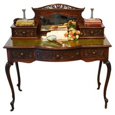 an antique desk with flowers and books on it