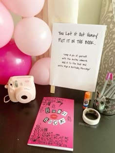 a table with balloons, a camera and a sign that says you let it out honey put it in the book