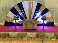 the stage is decorated with blue and white draping, two flower vases on each side