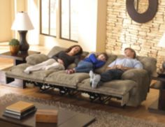 three people laying on a couch in a living room