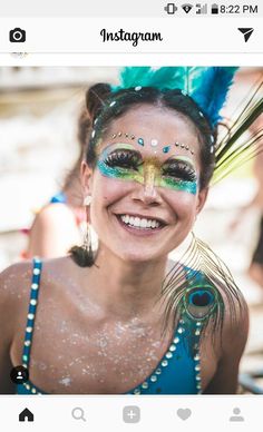 a woman with face paint and feathers on her head smiles for the camera while smiling