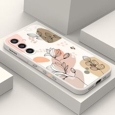 an iphone case with flowers and leaves on the back, sitting on top of a box