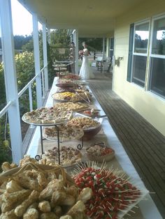 a long table filled with lots of food on top of a wooden floor next to a building