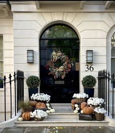 a front door with pumpkins and white flowers on the steps in front of it