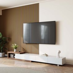 a flat screen tv mounted to the side of a wall in a living room next to a potted plant