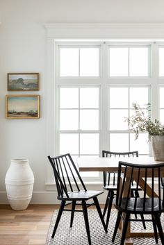 a dining room table with four chairs and a potted plant in the corner next to it