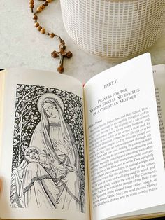 an open book sitting on top of a table next to a rosary and a cup