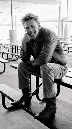 a black and white photo of a man sitting on a bench