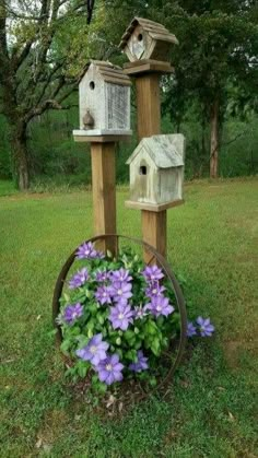 three bird houses sitting on top of wooden posts with purple flowers in the foreground