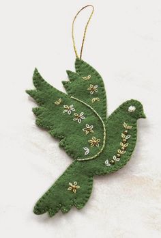 a green bird ornament hanging on a white background with gold stars and beads