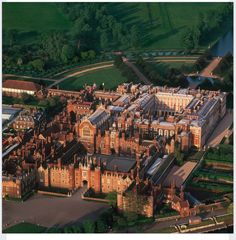 an aerial view of a large building in the middle of a green field with trees