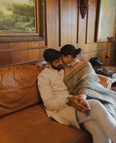 a man and woman sitting on top of a brown couch