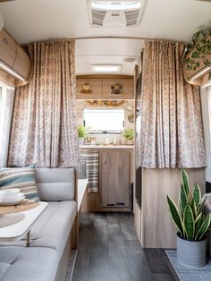 the interior of an rv with curtains, couches and table in front of it