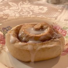 a cinnamon roll on a plate with icing drizzled over the top