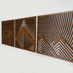 three pieces of art made out of wood with geometric designs on the wall behind them