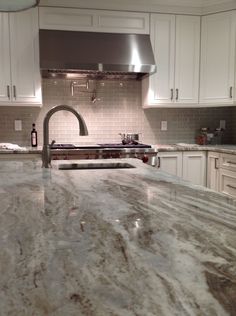 a kitchen with marble counter tops and stainless steel range hood over the stove, oven and dishwasher