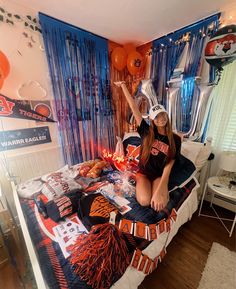 a woman sitting on top of a bed in a room with orange and blue decorations