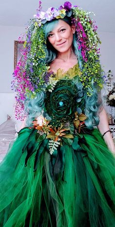 a woman wearing a green dress with flowers on her head and hair in the middle