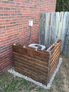 a wooden box with a water heater attached to it next to a brick wall