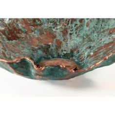 a green bowl with copper accents on it