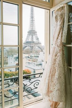 wedding dress hanging in front of window with eiffel tower in the back ground