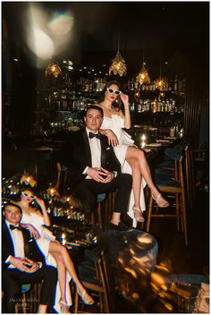 a man and woman sitting next to each other in front of a bar at night