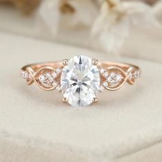 a rose gold engagement ring with an oval center stone surrounded by small white diamond accents